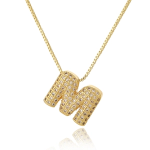 Macro shot of gold M-letter pendant with micro-pave zircons on a box chain