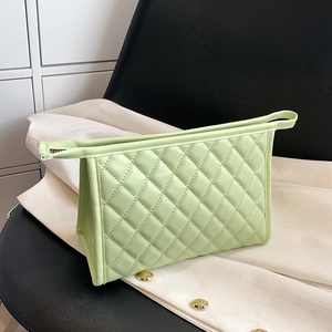 Light green quilted makeup bag with zipper closure on a stylish black and white background