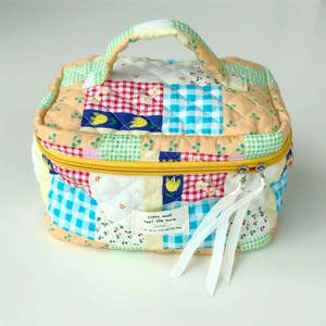 Detail of colorful patchwork quilted cosmetic bag with ribbon zipper pull and brand tag