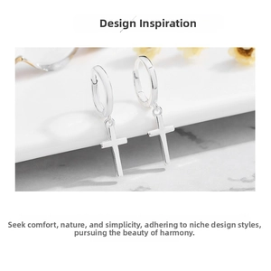 Macro shot of minimalist S925 sterling silver cross hoop earrings on white marble surface