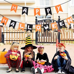 Detalle de niños bajo pancarta de Happy Halloween con calabazas y dulces afuera