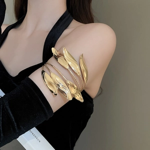 Close-up of a polished gold multi-layer leaf arm cuff on a model's upper arm