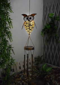 Solar powered owl wind chime with bronze finish and hollow pattern glowing at night
