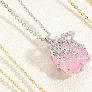 Macro shot of pink heart zircon pendant with silver leaf branch design on white leather