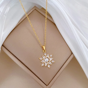 Macro view of gold titanium necklace with pearl sunflower pendant and crystals