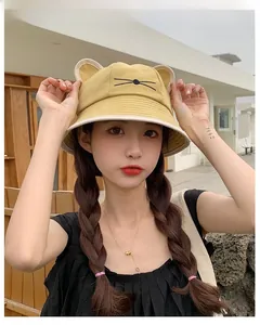 Detail of yellow canvas bucket hat featuring 3D cat ears and whiskers embroidery