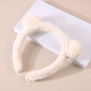 Detail of plush cream headband with fluffy pom-pom ears for skincare and makeup