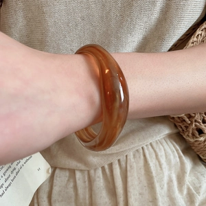 Close-up of amber translucent acrylic bangle on wrist with a minimalist natural style