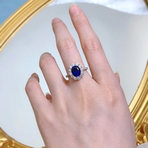 Close-up of a classic oval sapphire ring with sparkling zircon halo and silver band