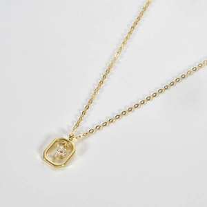 Detailed macro shot of a gold geometric hexagon pendant with a zircon-encrusted letter P