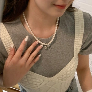 Detail view of pearl bow necklace worn by a model to show elegant fit and drape