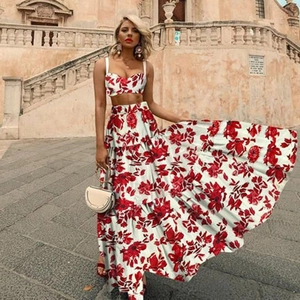 Detail of summer two-piece set with red floral print crop top and maxi skirt on white fabric