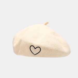 Detailed view of beige wool beret featuring a delicate black embroidered heart pattern