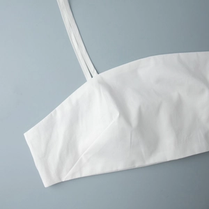 Détail de la coupe de poitrine et des coutures de bretelles fines sur caraco blanc en coton