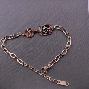 Detail of rose gold stainless steel bracelet with Lucky round charm and square angel pendant