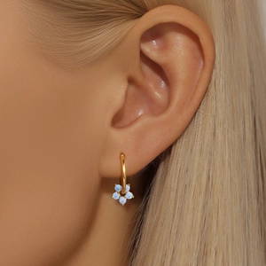 Macro view of light blue opal flower charm hanging on a golden sterling silver earring hoop