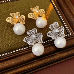 Detail view of vintage flower zircon and pearl earrings on premium green velvet background