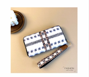 Detail of white leather purse with ethnic geometric print and gold metal zipper hardware