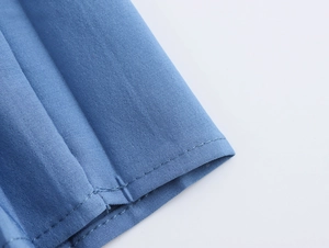 Makroaufnahme vom Saum des blauen Tweed-Kleides mit Fokus auf die Naht und Stoffstruktur