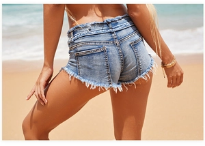 Rückansicht von Denim-Shorts mit ausgefranstem Saum vor sonnigem Strandhintergrund