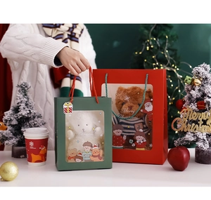 Close-up of a green Christmas gift bag with a plush bear toy and festive holiday props