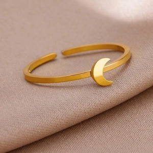 Close-up of a gold celestial crescent moon open ring on a soft silk fabric background