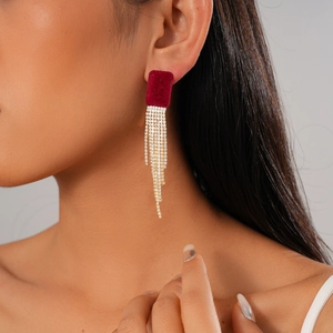 Gros plan de boucles d'oreilles en velours bordeaux avec pompons en strass argentés