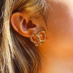 Close-up of 18K gold stainless steel heart knot earrings with diamonds on a model