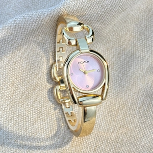 Close-up of gold horseshoe-shaped watch case with pink dial and four diamond markers