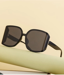 Detail of black oversized square sunglasses on a geometric stand with metal accents