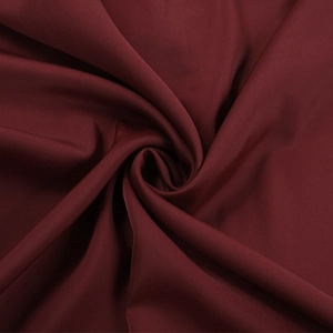 Macro shot of silky dark red satin fabric with elegant drapes and smooth texture