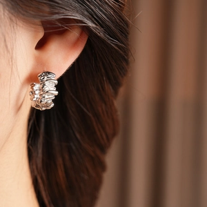 Close-up of silver irregular lava texture C-shape hoop earring worn by a model