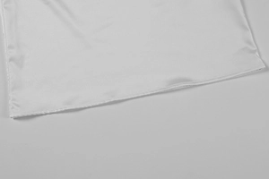 Detailed view of fine stitching on the white silk fabric hem with smooth satin finish