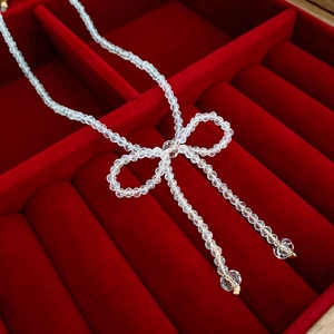 Macro shot of clear beaded crystal bow necklace displayed in a red velvet jewelry box