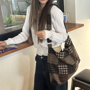 Dettaglio della borsa tote vintage a quadri marroni con ampia tracolla su modella