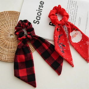 Detail view of festive buffalo plaid and Santa Claus pattern ribbon hair scrunchies