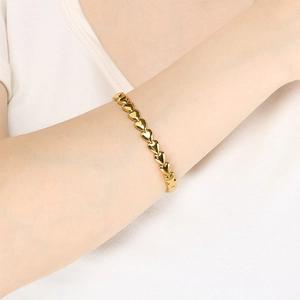Detailed close-up of polished gold heart links bracelet on wrist with elegant finish