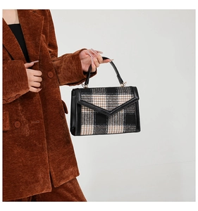 Detaillierte Nahaufnahme des Vintage-Hahnentrittmusters und der Goldbeschläge am Handtasche