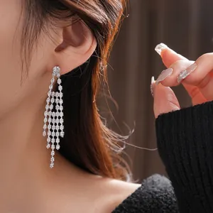 Elegant silver tassel earrings with marquise-cut zircons worn by model on black background