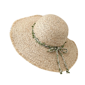 Handwoven raffia sun hat with wide brim, green leaf ribbon, and fringe edge detail