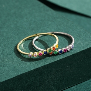 Bagues chic en or et argent serties de zircons multicolores sur fond vert texturé