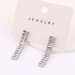Close-up of dangling silver earrings featuring a row of rectangular step-cut cubic zirconia