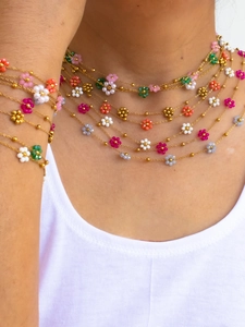 Macro shot of colorful beaded flower necklace and bracelet set on a white model top