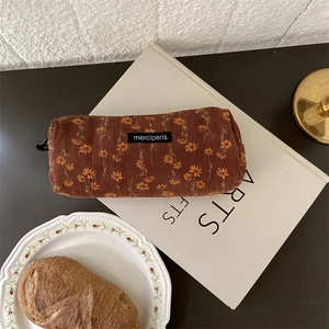 Detail view of brown corduroy pencil case with yellow floral pattern and brand label