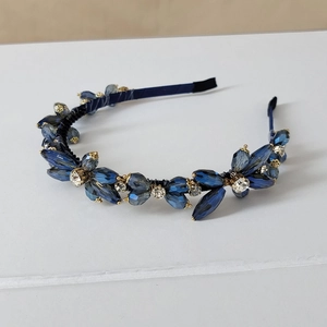 Detail of dark blue crystal flower ornaments on a luxury fabric headband with gold settings