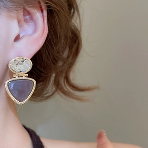 Detail of 18k gold plated triangle pendant earring with crystals worn by model