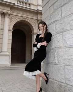 Dettaglio in pizzo bianco su abito in velluto nero con sfondo di architettura europea d'epoca
