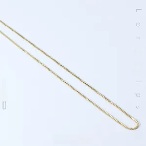 Close-up of a minimalist golden stainless steel box chain necklace with polished texture