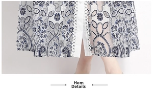 Nahaufnahme von weißem Spitzenkleid-Saum mit blauem Blumendruck und Ösen-Detail