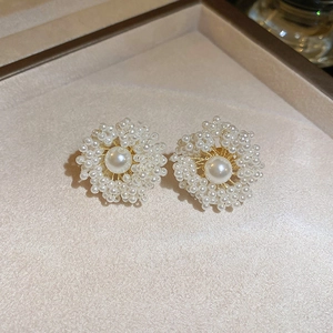 Macro view of handmade pearl flower cluster earrings with delicate gold weaving
